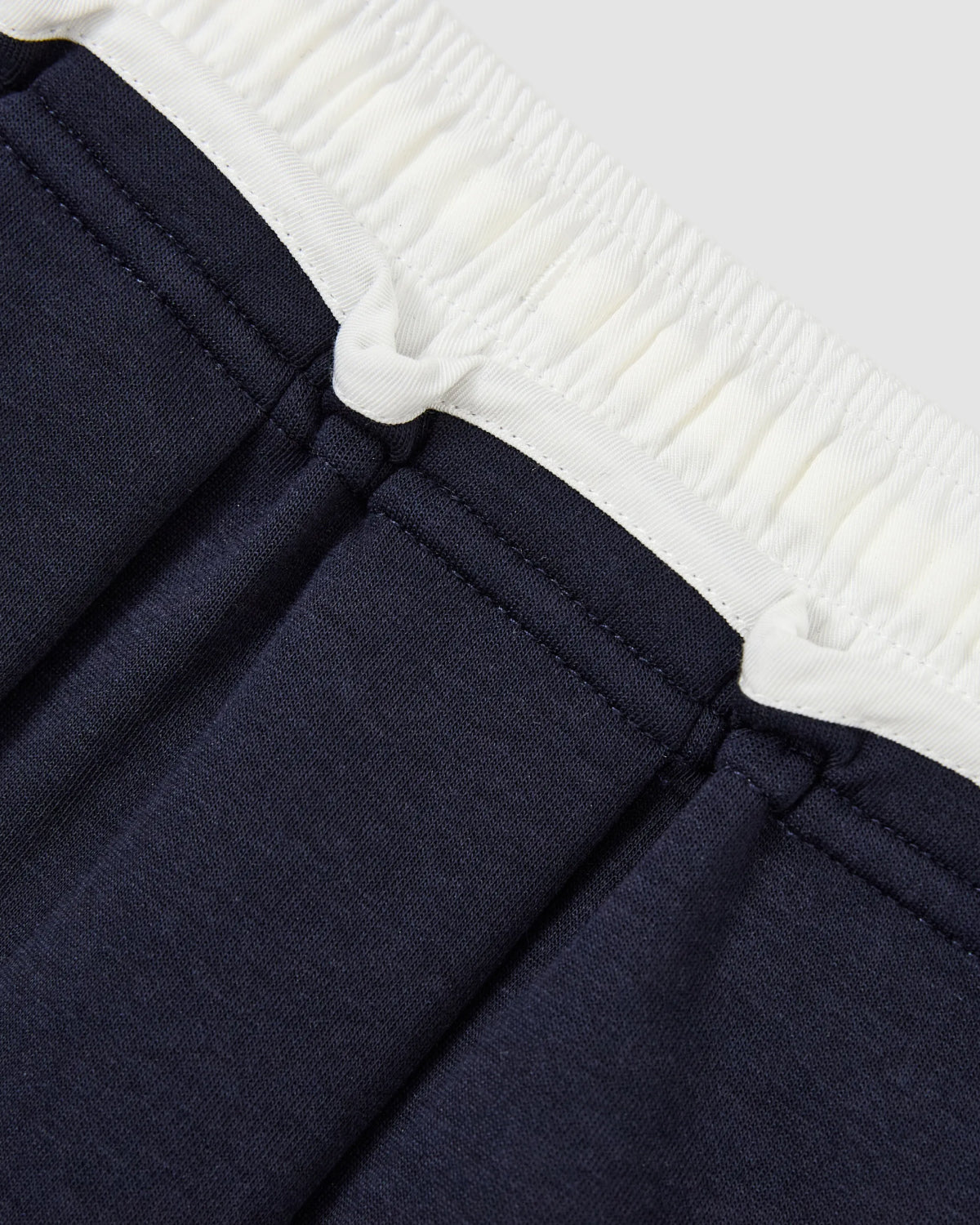 Close-up of the waistband on the Sundae School NAVY PLEATED JERSEY MINI SKIRT, featuring a white elasticated band and stitched seam details.