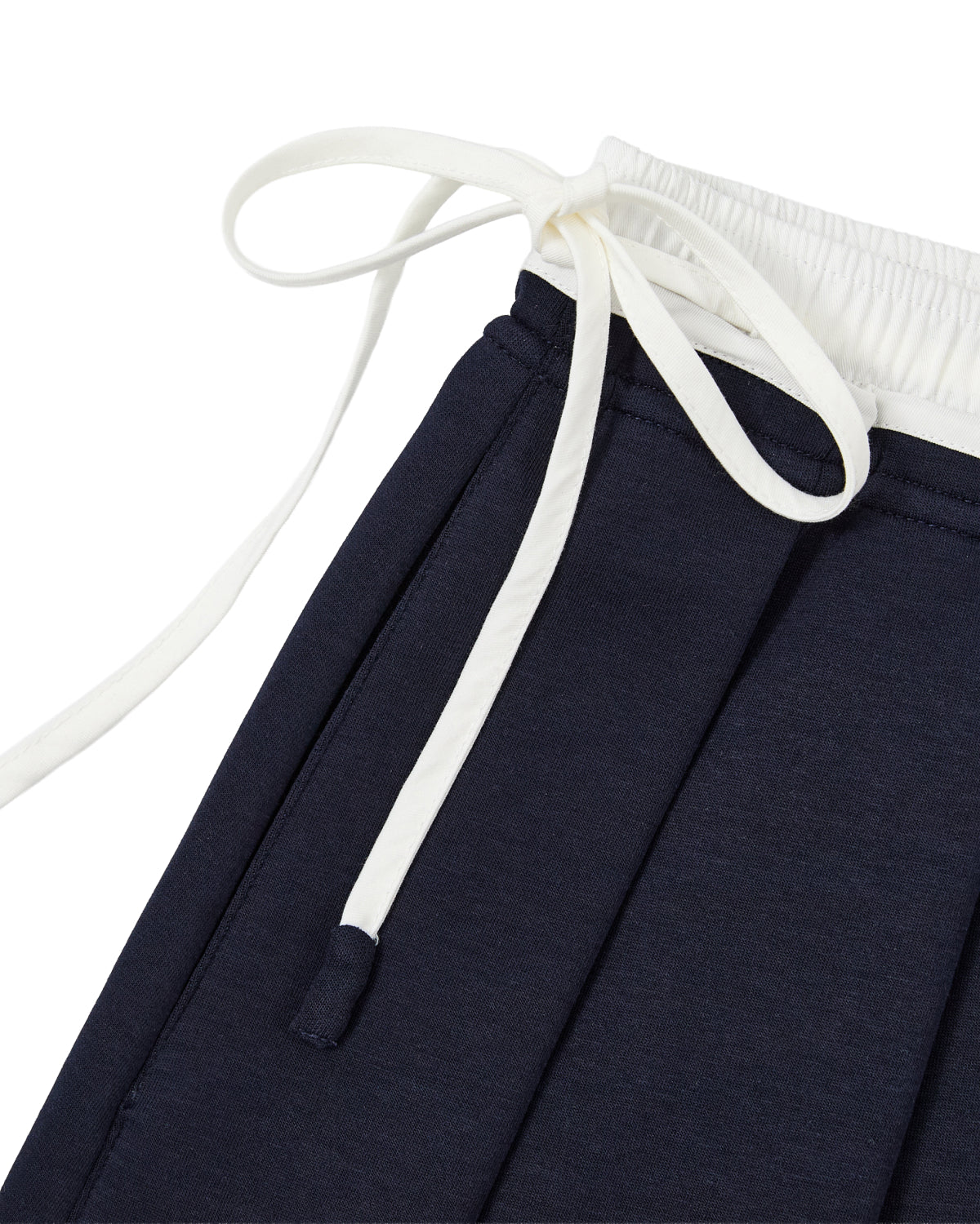 Close-up of the NAVY PLEATED JERSEY MINI SKIRT by Sundae School, featuring a navy blue cotton blend with an elastic white waistband and white drawstrings tied in a bow, designed for a comfortable fit.