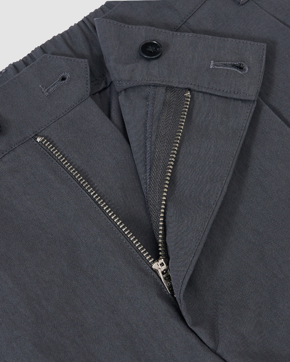 Close-up of Sundae School’s CHARCOAL PLEATED UNIFORM SLACKS, inspired by classic Korean school uniforms, featuring an open zipper fly and two buttons at the waistband.