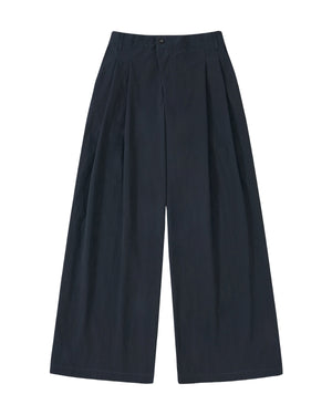 The Sundae School NAVY PLEATED UNIFORM SLACKS feature a high-waisted, wide-leg design with front pleats and side pockets, inspired by modern Korean gyobok and photographed laid flat on a plain light background.