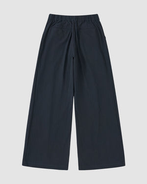 Sundae School NAVY PLEATED UNIFORM SLACKS feature a wide-leg fit, elastic waistband, and side pockets. Shown flat on a white background in back view, these slacks give a modern update to classic Korean gyobok style.