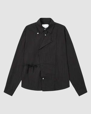 The BLACK POPLIN TIE GORUM SHIRT by Sundae School, featuring long sleeves, an asymmetrical front, button closures, and a side tie detail, is displayed on a plain light grey background.