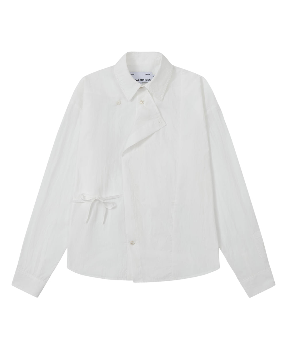 The WHITE POPLIN TIE GORUM SHIRT by Sundae School is a unisex, tailored-fit white long-sleeve shirt crafted from cotton nylon poplin. It features an asymmetrical front, classic collar, and distinctive side tie detail, with a double-layered front panel adding dimension. Shown on a plain background.