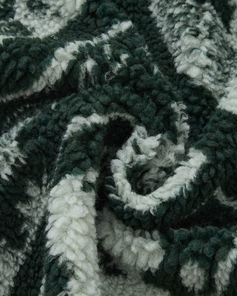 Close-up of the soft, textured TEAL REVERSIBLE GOSTOP FLEECE by Sundae School, featuring green and white stripes and plush sherpa fabric, loosely bunched and folded to showcase its fluffy, cozy surface—perfect for a stand collar zip up or hwatu jacket.