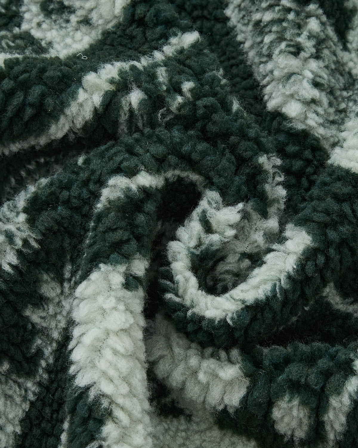 Close-up of the soft, textured TEAL REVERSIBLE GOSTOP FLEECE by Sundae School, featuring green and white stripes and plush sherpa fabric, loosely bunched and folded to showcase its fluffy, cozy surface—perfect for a stand collar zip up or hwatu jacket.