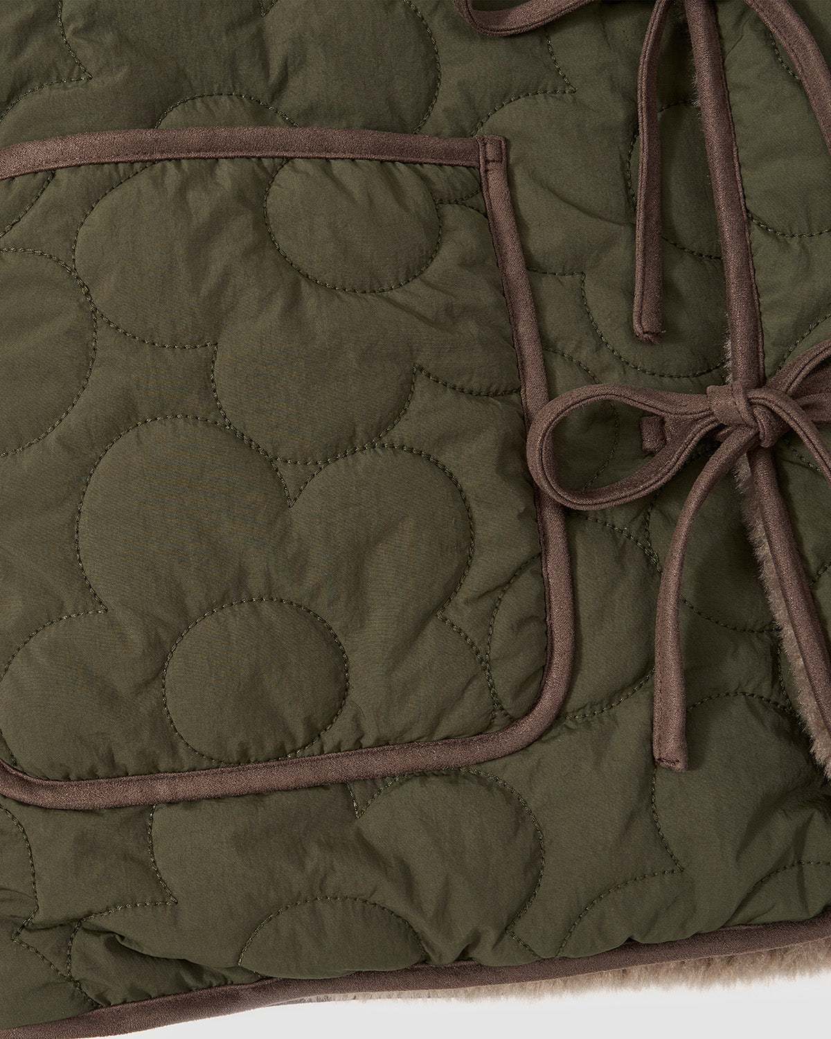 Close-up of a quilted front pocket with brown trim on the olive green circular-patterned Reversible Flower Quilted Jeogori Fleece.