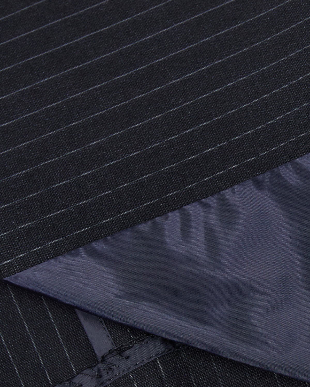 Close-up of the SABRINA VEST by Sundae School: dark pinstripe summer wool with thin white lines, partially overlaid by smooth, dark satin lining that has a subtle sheen and overlaps the pinstripe at an angle.