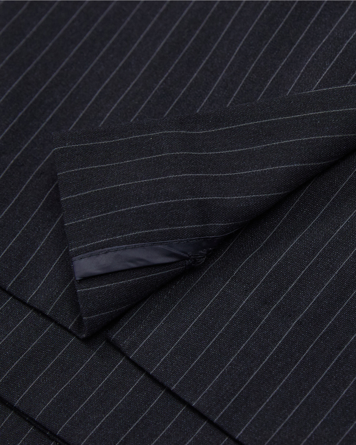 Close-up of the SABRINA VEST by Sundae School, featuring dark pinstripe summer wool with thin white stripes and black inner lining visible at the cuff.