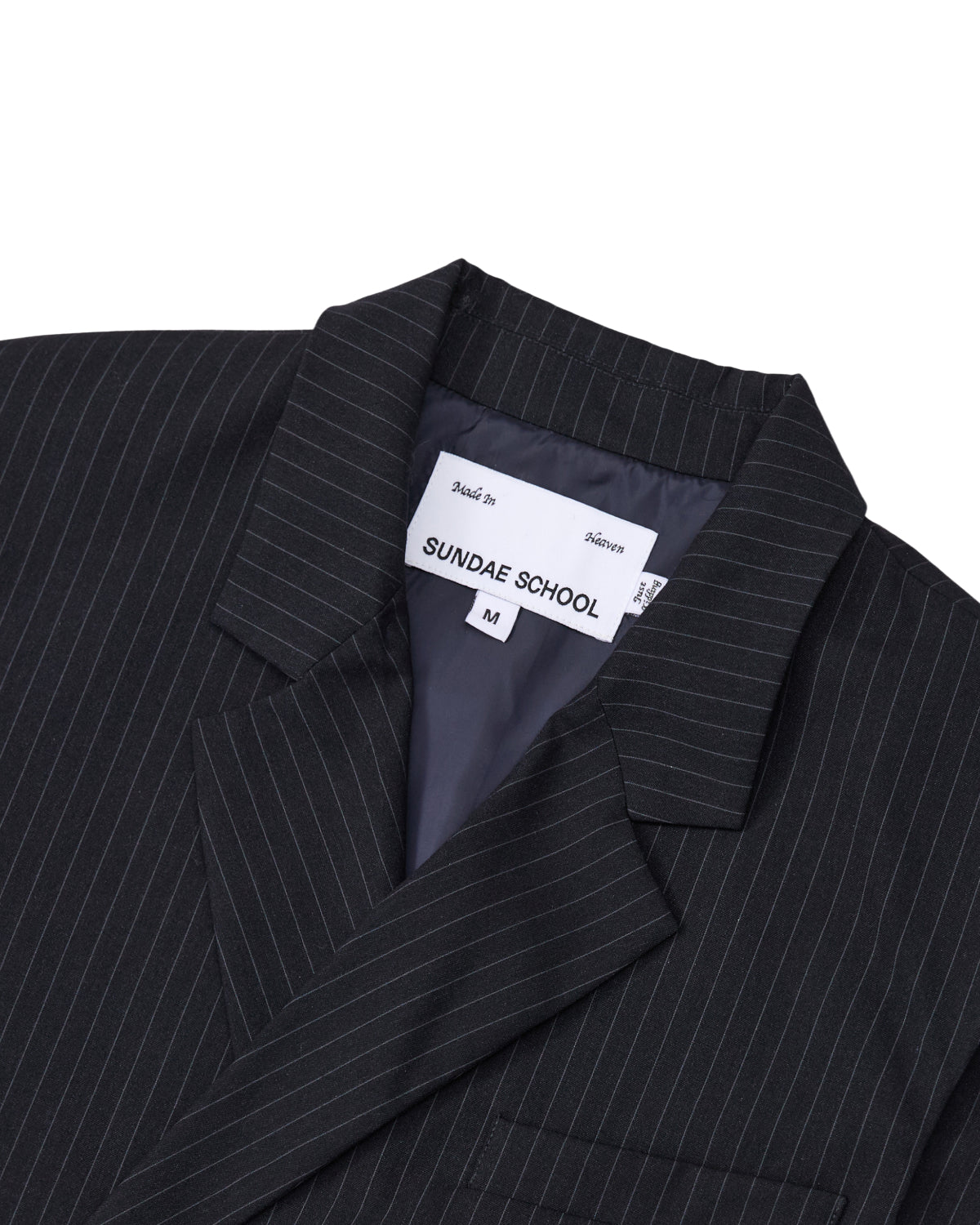 Close-up of the SABRINA VEST in a black pinstripe rayon blend, featuring a visible Sundae School label and size M inside the collar. The inner lining is dark and smooth, and the vest showcases classic lapels.