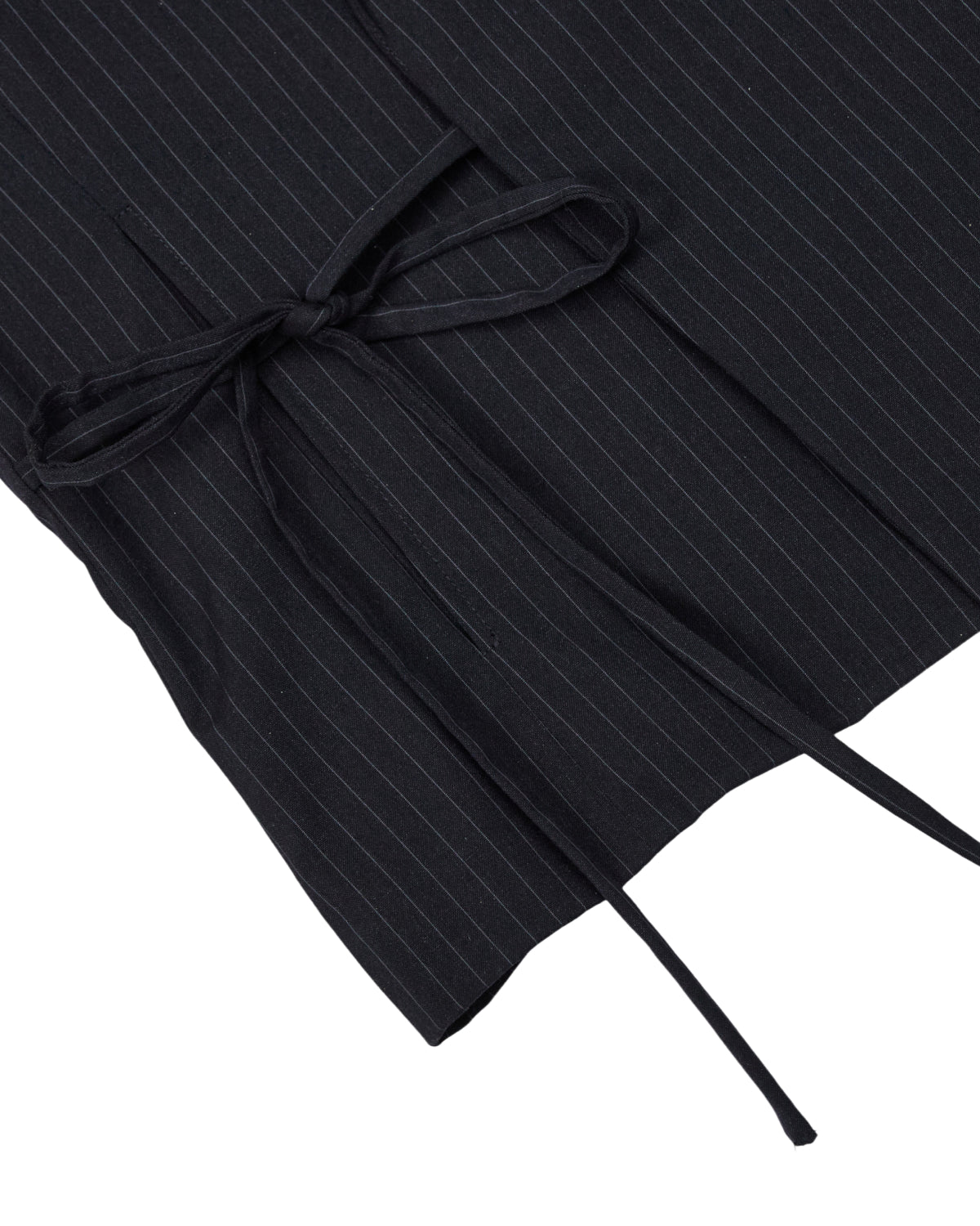 Close-up of the SABRINA VEST by Sundae School, crafted from a black rayon blend pinstripe fabric with thin white stripes, featuring a matching fabric belt tied in a neat bow inspired by the traditional Korean goreum tie.