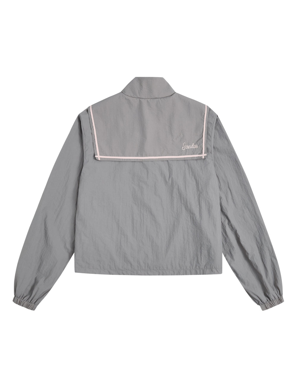 The GREY SAILOR WINDBREAKER by Sundae School is a light gray long-sleeve jacket designed in a classic sailor style, complete with a distinctive back flap, crisp white trim, and a small embroidered logo on the upper right. Crafted from lightweight, slightly textured fabric, this cropped windbreaker is perfect for breezy days.