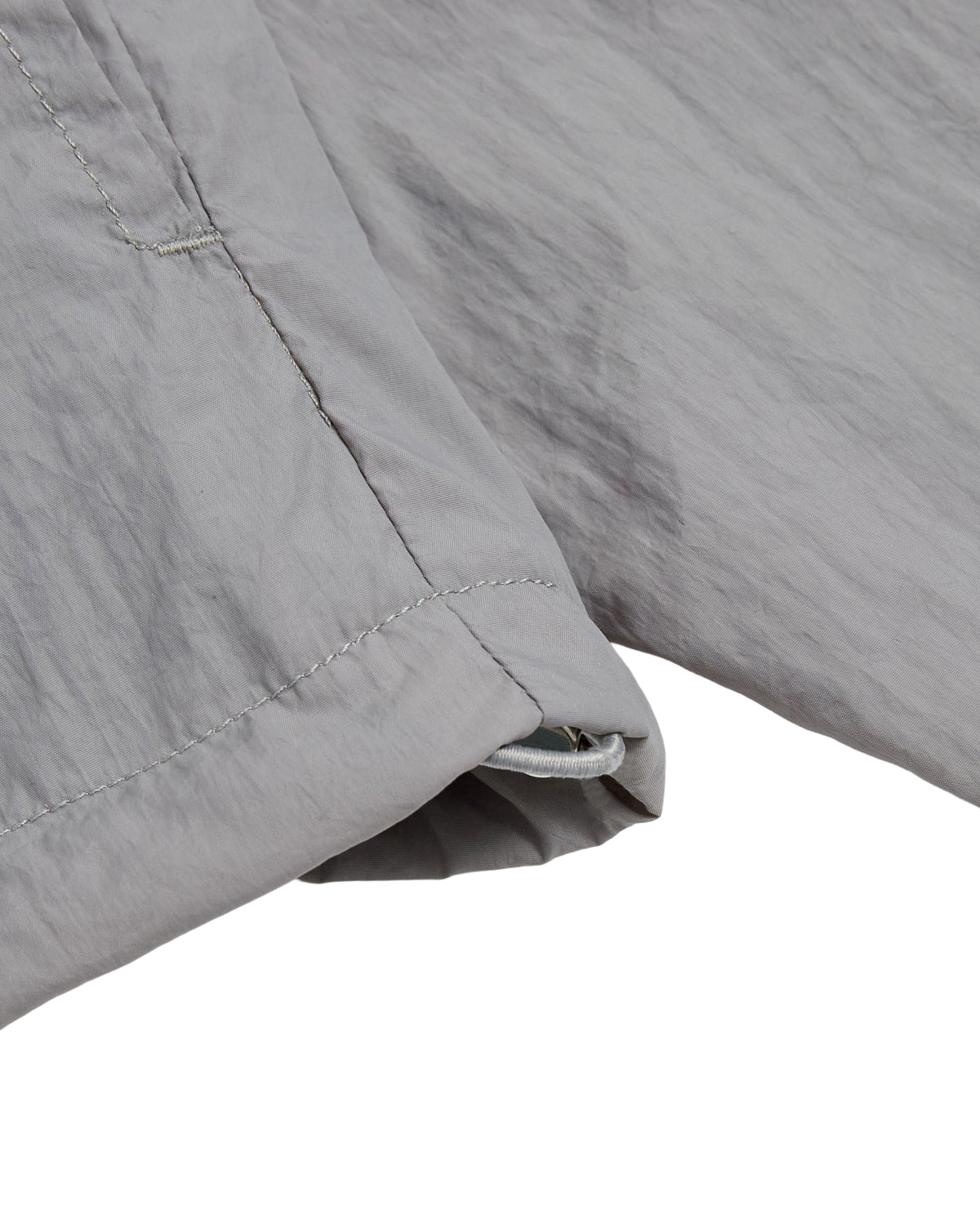 A close-up of the cuff and seam of the GREY SAILOR WINDBREAKER by Sundae School, highlighting the detailed stitching and textured light gray, lightweight fabric of the cropped sleeve.