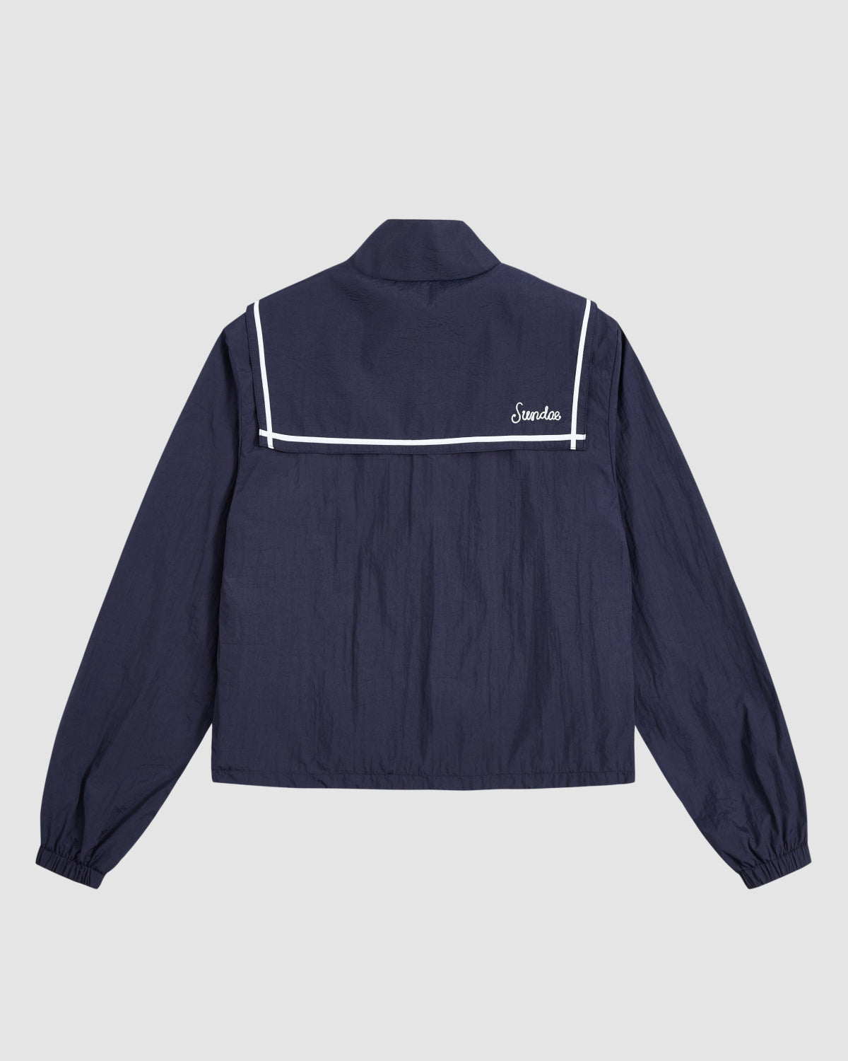 The NAVY SAILOR WINDBREAKER by Sundae School is a navy cropped jacket with long sleeves, white-bordered sailor collar, and 