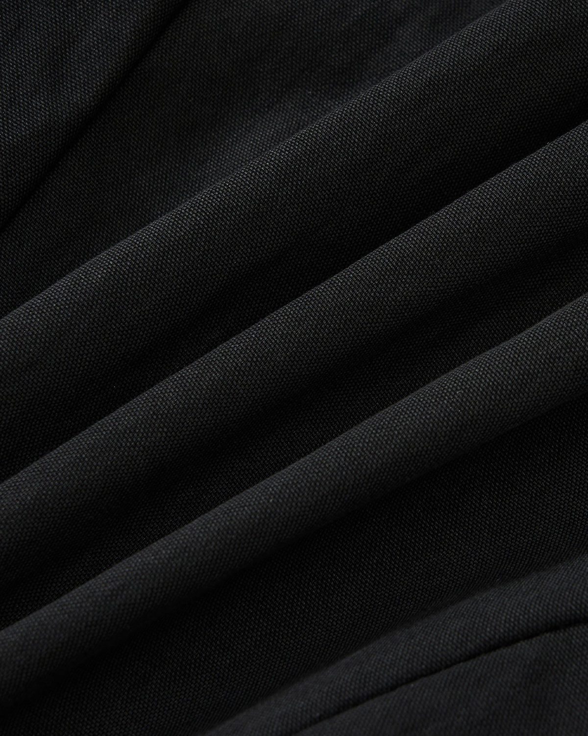 Close-up of the BLACK SAILOR COLLAR UNIFORM JACKET by Sundae School, showing black fabric with soft folds and subtle mochi quilted stitching that forms diagonal lines and shadows across its textured surface.