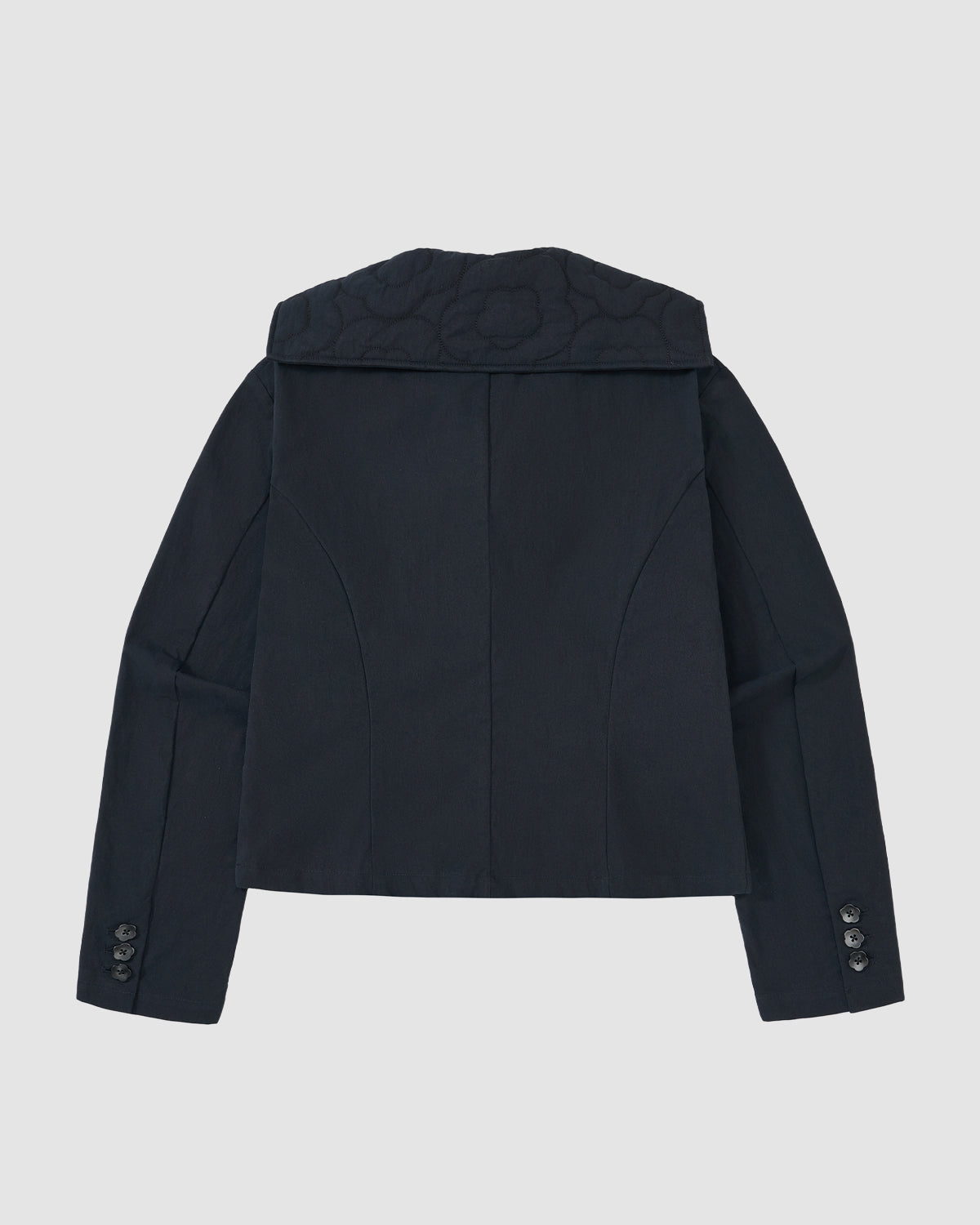 The NAVY SAILOR COLLAR UNIFORM JACKET by Sundae School is shown from the back, featuring a wide sailor collar, subtle seam details, buttoned cuffs on both sleeves, and a mochi quilted textured finish.