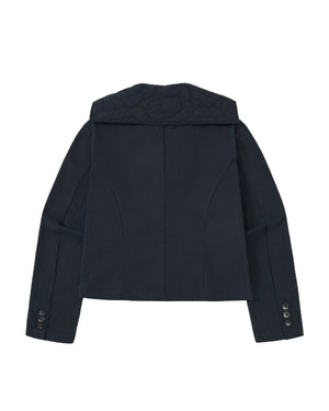The NAVY SAILOR COLLAR UNIFORM JACKET by Sundae School is shown laid flat to display the back. This dark navy blue jacket features long sleeves with buttoned cuffs, wide lapels, and subtle stitched details at the distinctive sailor collar—evoking traditional Korean school uniform styles.