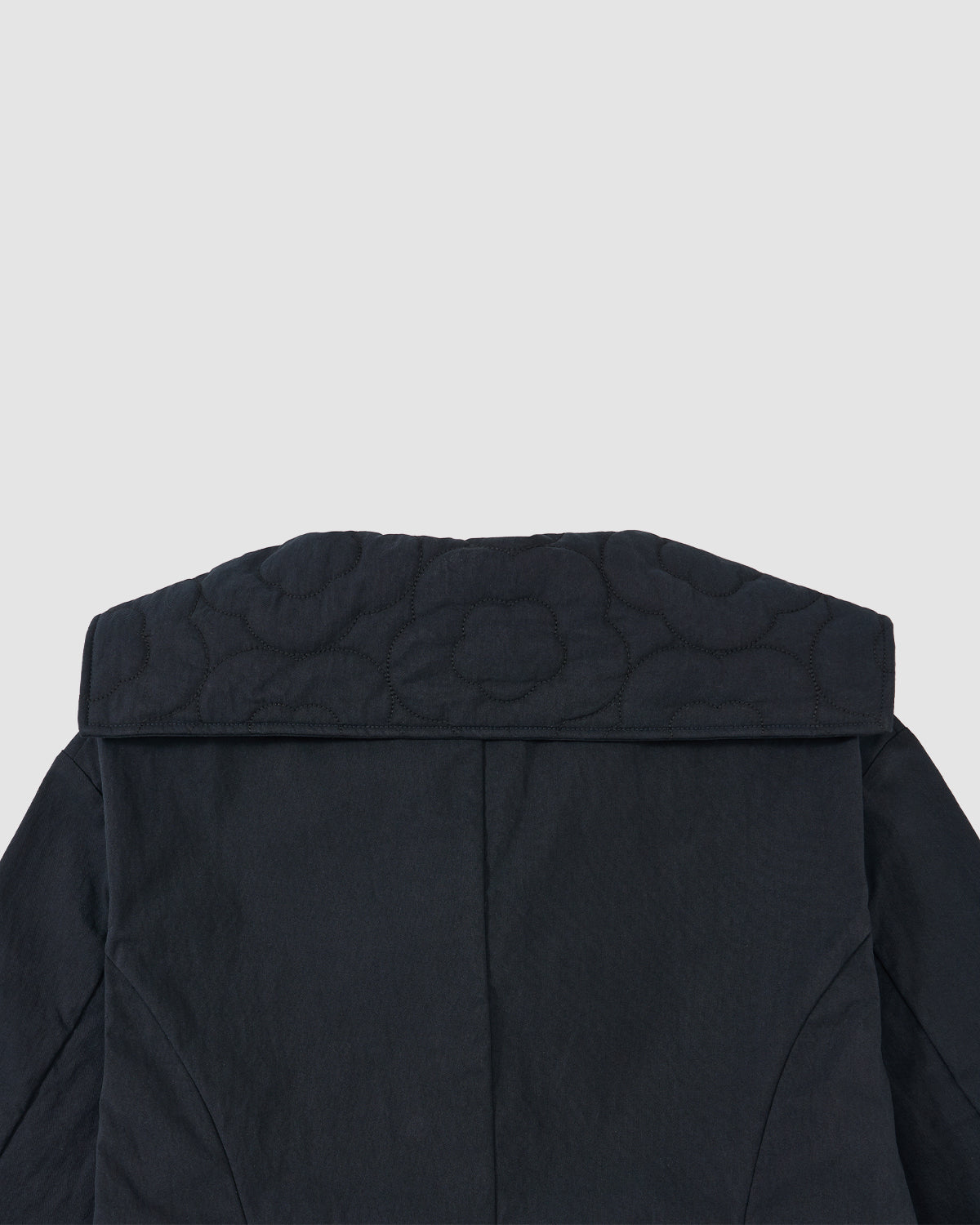 Close-up of the back of the NAVY SAILOR COLLAR UNIFORM JACKET by Sundae School, featuring mochi quilted floral stitching against a light gray background.