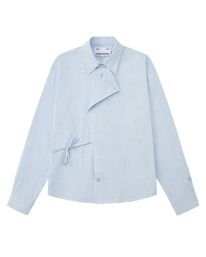 A front flat-lay view of a light blue long-sleeve button-up shirt in a textured seersucker fabric. It features a Korean Hanbok-inspired asymmetrical wrap-front flap, a side tie closure at the waist, a pointed collar, and subtle flower-shaped button accents.