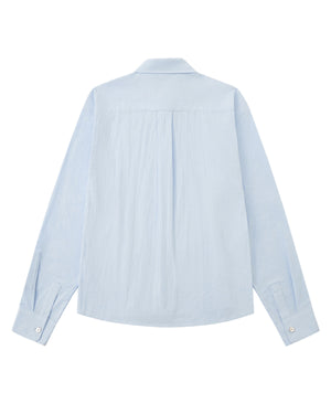 A back flat-lay view of a light blue long-sleeve shirt laid flat against a white background, showing a clean shoulder yoke, a central back box pleat, and buttoned cuffs.