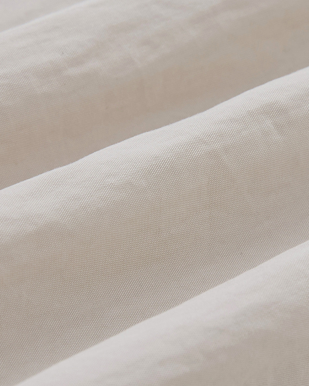 Close-up of the IVORY SHAWL COLLAR ANORAK by Sundae School, showcasing the soft cotton-nylon shell in off-white with visible texture and gentle diagonal folds for a smooth, refined appearance.