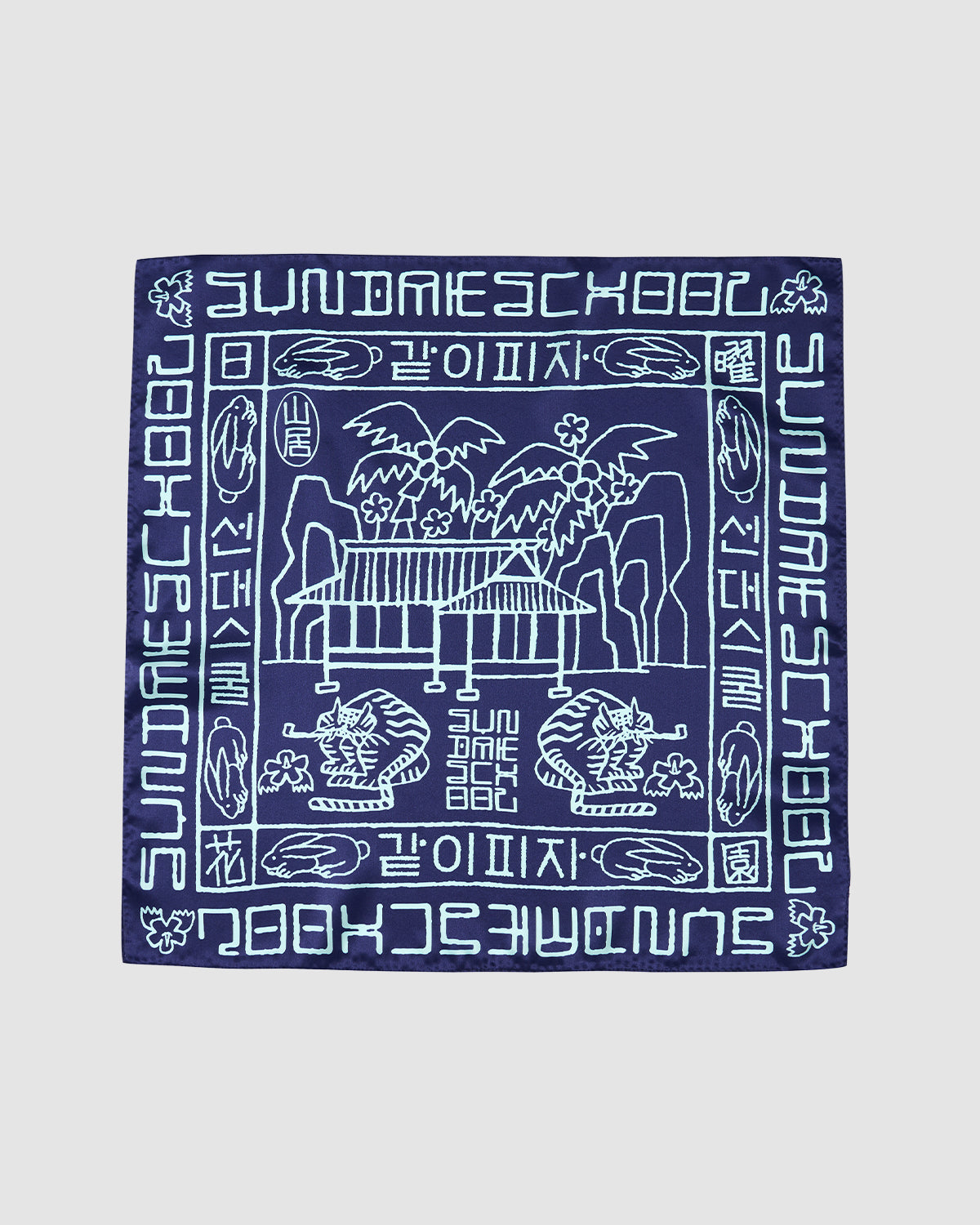 The NAVY SILK BANDANA by Sundae School features light blue line illustrations of palm trees, benches, and tigers with stylized Hangeul script and “SUNDAY SCHOOL” in English and Korean around the border.