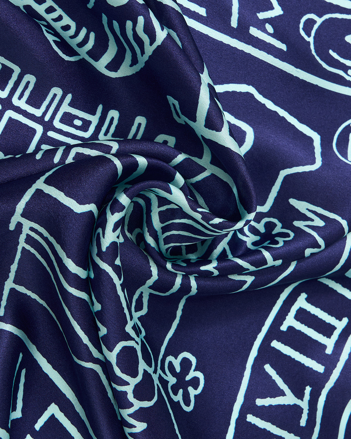 A close-up of Sundae School's NAVY SILK BANDANA reveals deep blue silk with light blue geometric patterns inspired by Korean folk design, featuring soft folds and a smooth, shiny texture.