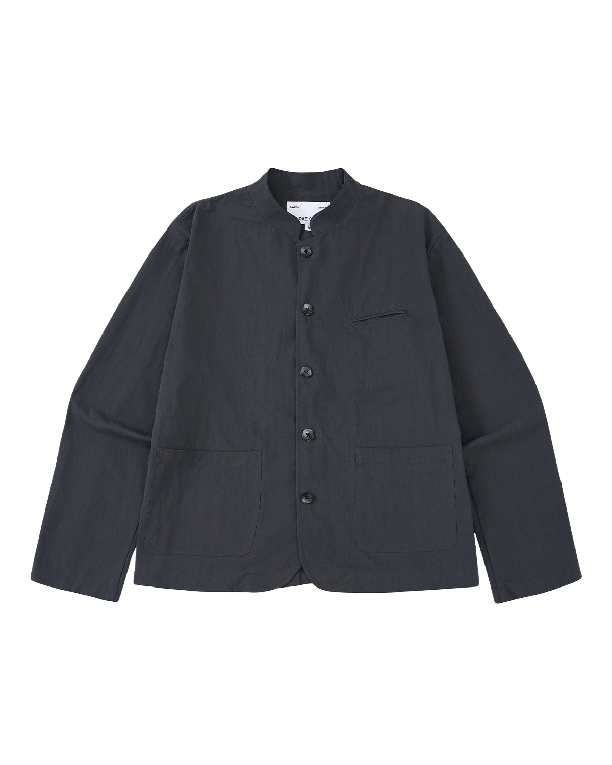 The Sundae School CHARCOAL STAND COLLAR UNIFORM JACKET, made from a cotton-nylon blend with long sleeves and three front pockets, is shown laid flat on a light gray background.