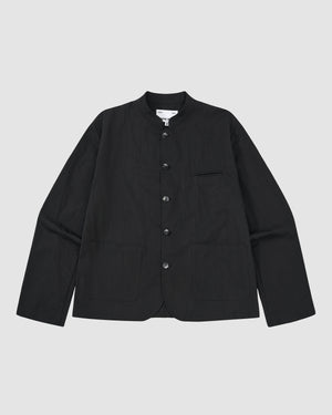 The BLACK STAND COLLAR UNIFORM JACKET by Sundae School is a black, wrinkle-resistant cotton-nylon jacket with long sleeves, button-up front, mandarin collar, two large front pockets, and a chest pocket, shown on a light gray background.