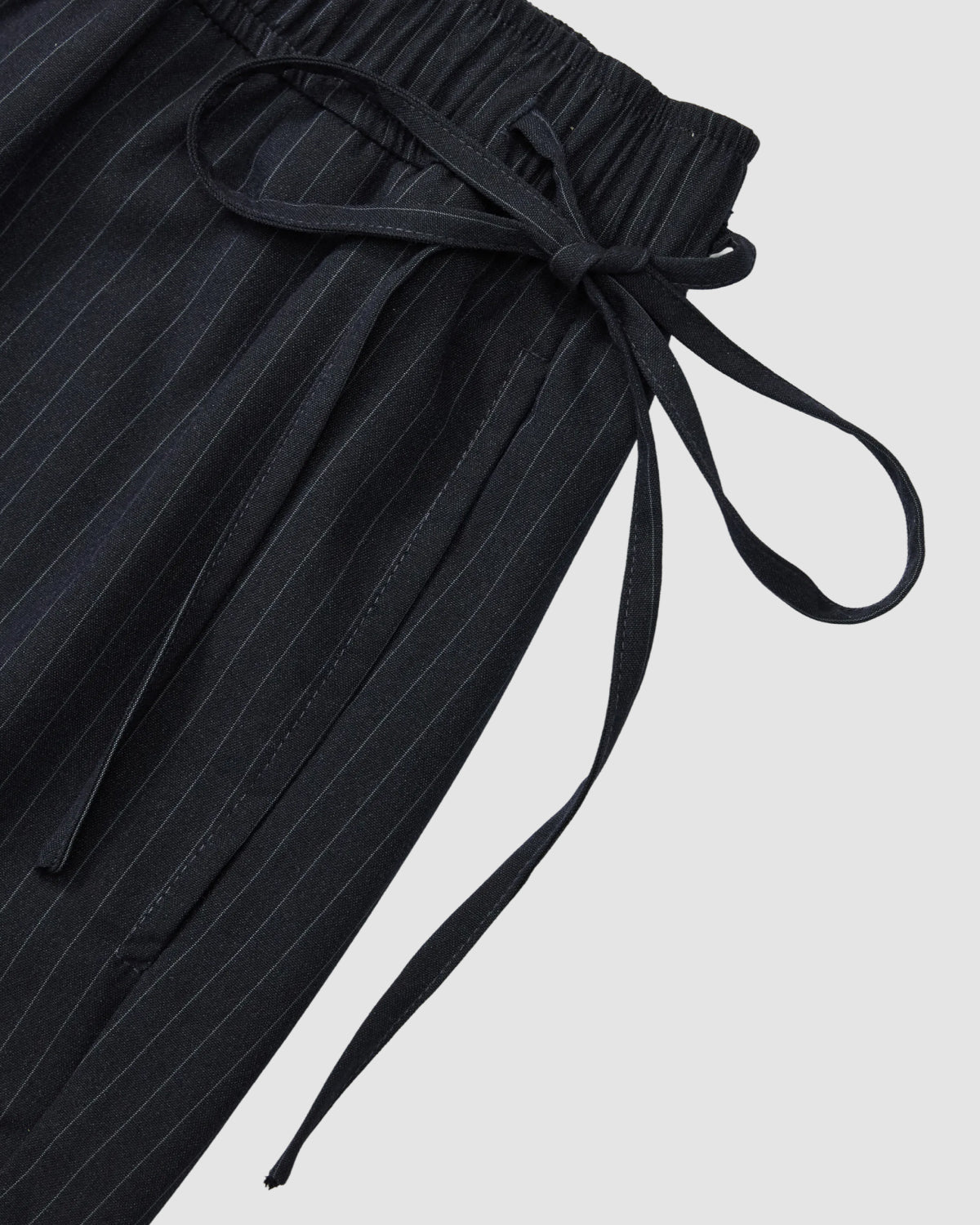 Close-up of Sundae School's Navy Stripe Boxer Shorts, crafted from a soft Tencel-rayon blend with an elastic waistband and tied fabric belt, displayed on a light gray background.