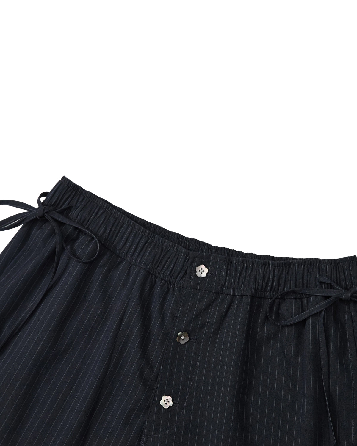 Close-up of the waistband of Sundae School’s STRIPED BOXER SHORTS, crafted from a lightweight rayon blend with dark pinstripes, featuring an elastic band, side drawstrings, and three visible buttons down the front—ideal for those wanting the comfort of work-from-home shorts with a polished look.