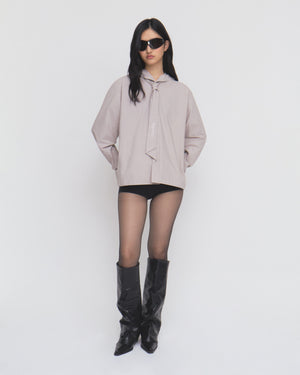 Model in black sunglasses, the Sundae School GREY SUNBAE TIE SHIRT, black shorts, sheer black tights, and black knee-high boots stands against a plain white background.