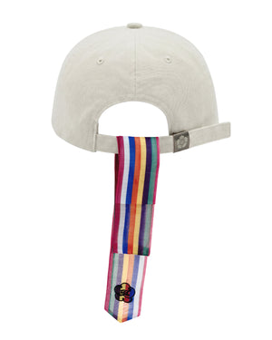 The IVORY DAENGGI CAP by Sundae School is an adjustable cotton cap in beige, featuring a rainbow-striped tie attached to the back strap and accented with a small flower patch near the end—a standout accessory for any Sundae School cap enthusiast.