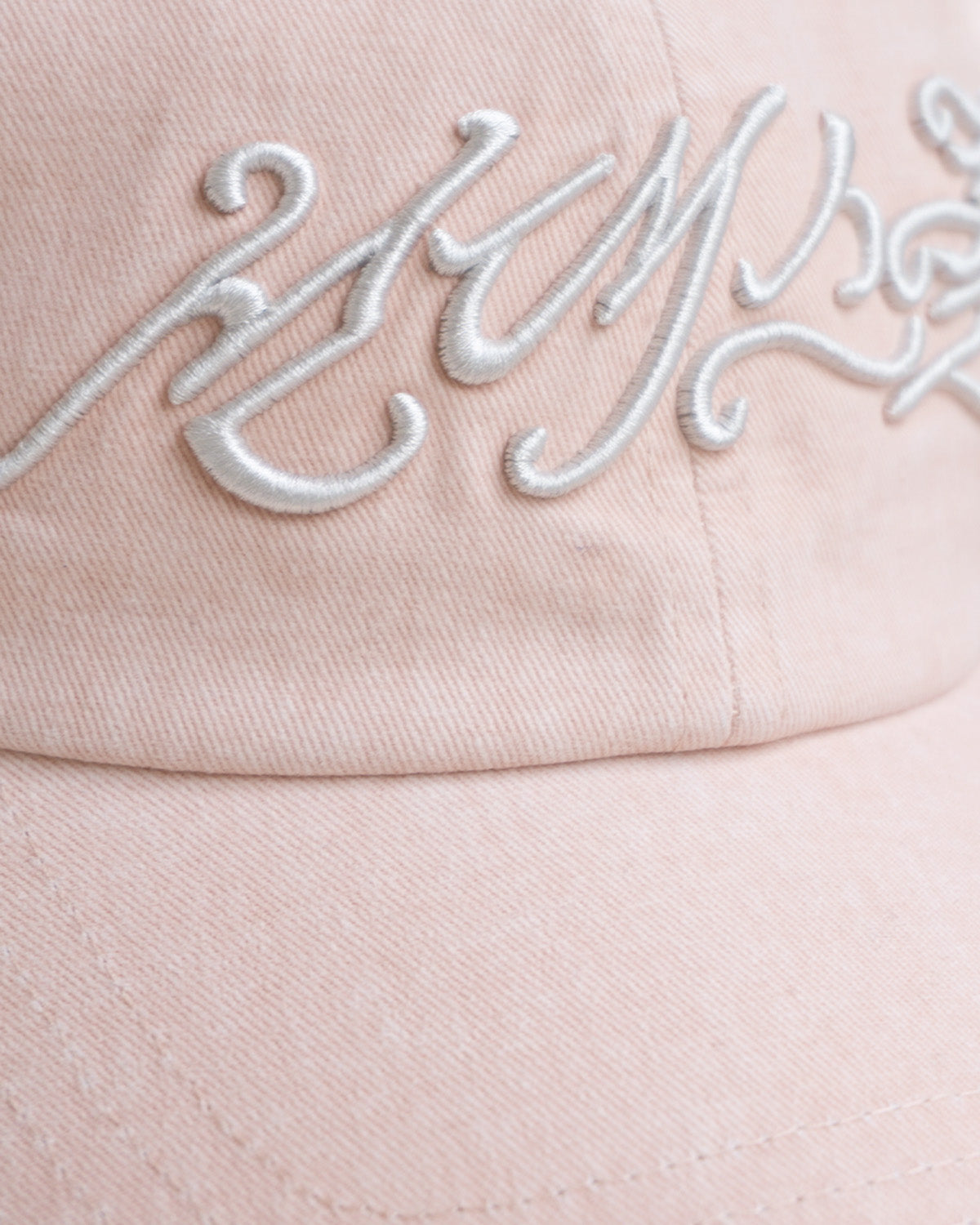A close-up of the BABY PINK DAENGGI CAP by Sundae School, an adjustable cotton cap in light pink with detailed white cursive embroidery across the front.