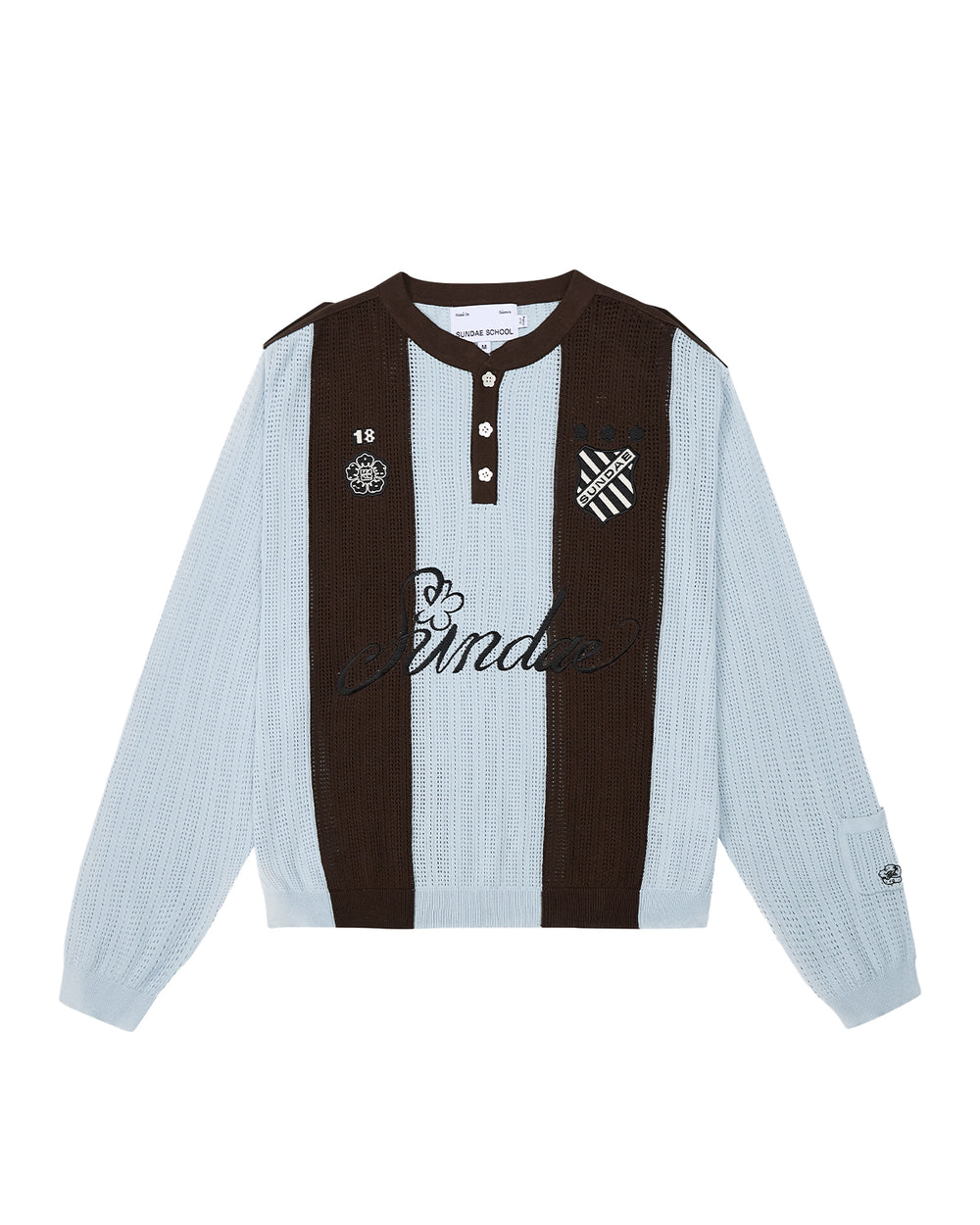 Sundae School SKY BLUE SUNDAE SOCCER JERSEY: This light blue and brown long-sleeve knit jersey features vertical stripes, a buttoned collar with unique floral mochi buttons, and embroidered chest patches—including a skull, heart, and “Banda” text—across the front.