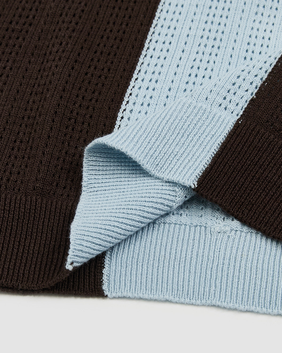 
Close-up detail showing contrast between light blue perforated mesh knit and brown ribbed knit textures from Baby Blue Brown Sundae Soccer Jersey Knit, demonstrating the technical sportswear fabric composition and vertical stripe pattern transition with ribbed cuff construction.