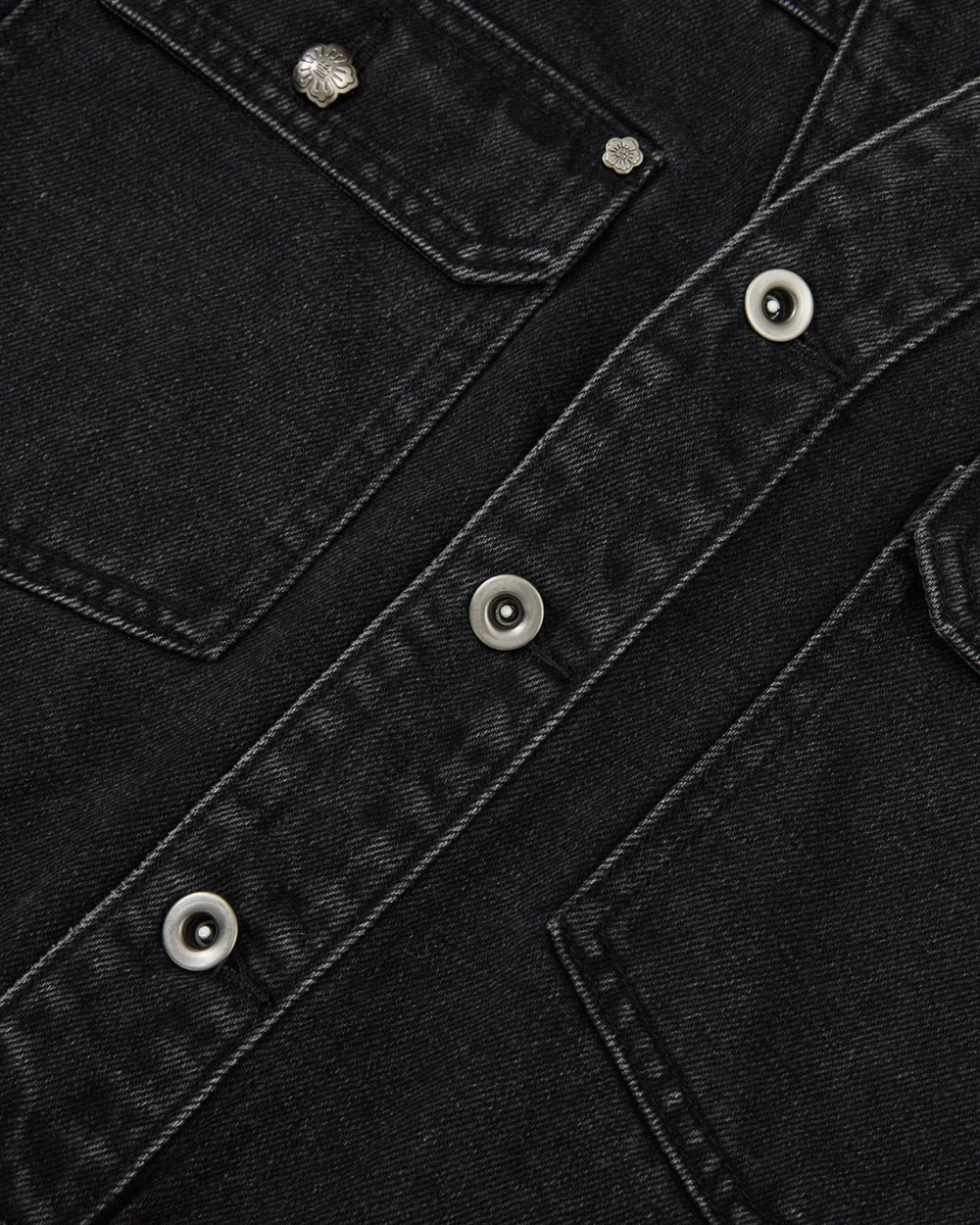 Close-up of the BLACK WIDOW TAEKWONDO DENIM JACKET by Sundae School, featuring a collarless design, visible stitching, metal snap buttons, and details of two front flap pockets—offering a modern twist on the classic Korean Canadian tuxedo style.