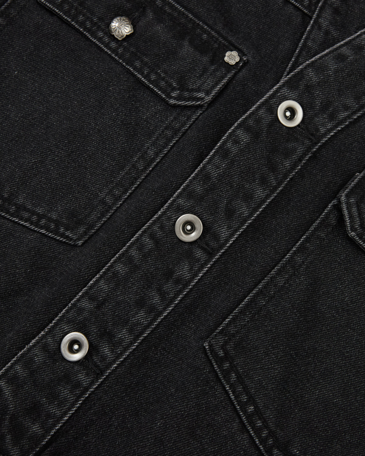 Close-up of the BLACK WIDOW TAEKWONDO DENIM JACKET by Sundae School, featuring a collarless design, visible stitching, metal snap buttons, and details of two front flap pockets—offering a modern twist on the classic Korean Canadian tuxedo style.