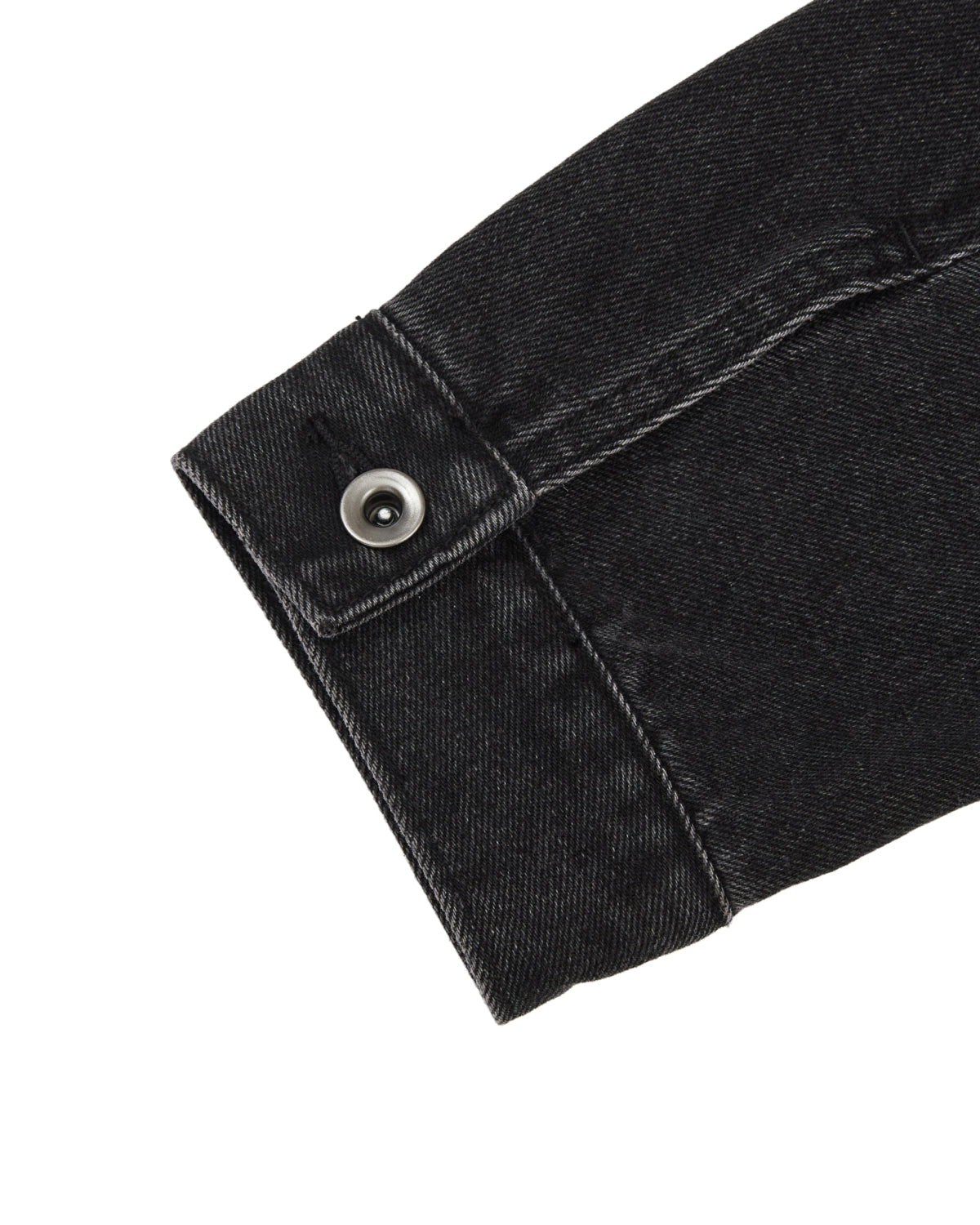 A close-up of the BLACK WIDOW TAEKWONDO DENIM JACKET sleeve by Sundae School, featuring visible stitching and a metal buttoned cuff, reminiscent of a collarless denim jacket often seen in the Korean Canadian tuxedo style, photographed against a white background.