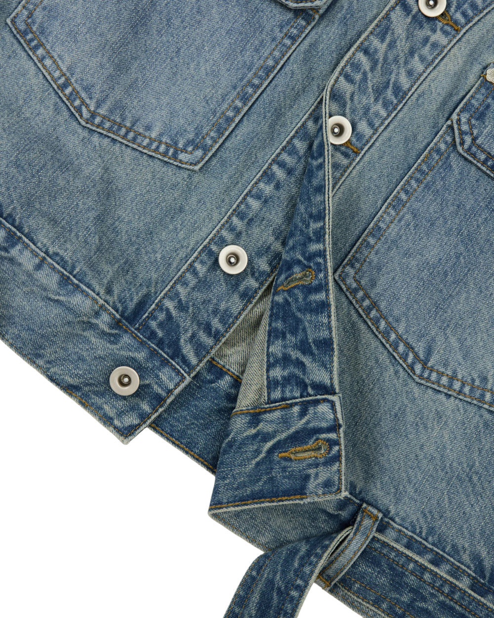 Close-up of the Sundae School MEDIUM BLUE TAEKWONDO DENIM JACKET, featuring metal buttons, visible stitching, and two front pockets, with part of the jacket unbuttoned to reveal a detachable belt-like strap at the hem—a modern reinterpretation of the classic Korean Canadian tuxedo.