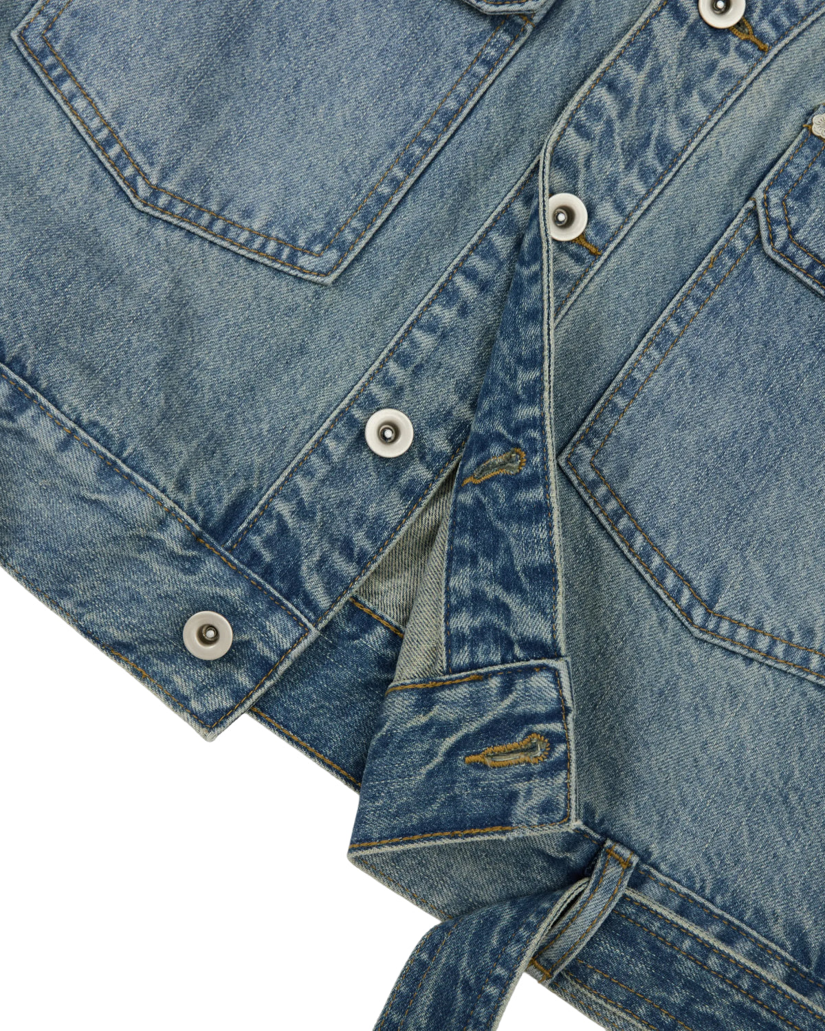 Close-up of the Sundae School MEDIUM BLUE TAEKWONDO DENIM JACKET, featuring metal buttons, visible stitching, and two front pockets, with part of the jacket unbuttoned to reveal a detachable belt-like strap at the hem—a modern reinterpretation of the classic Korean Canadian tuxedo.
