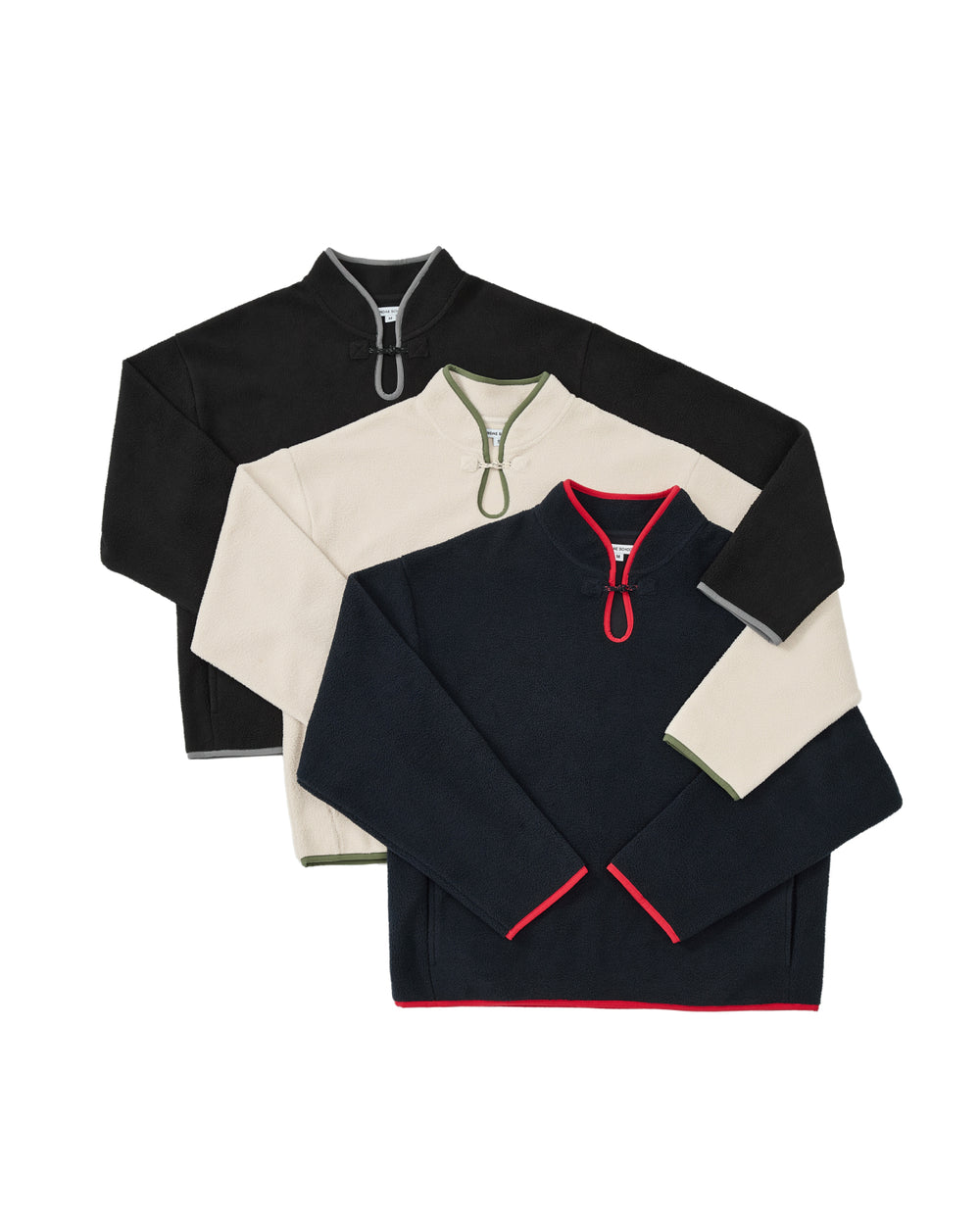 Three quarter-zip fleece pullovers are stacked. The top is the BLACK TEARDROP KNOT FLEECE by Sundae School, a cozy black fleece with a gray zipper; the middle is cream with green accents, and the bottom is navy with red trim and zipper detail.