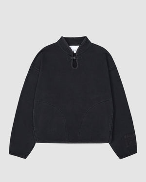 The BLACK TEARDROP KNOT SWEATSHIRT by Sundae School is a black cotton pullover with long sleeves, a short stand collar, V-neckline, drawstring detail, curved front seams, and a sleeve patch. Shown on a plain light gray background.