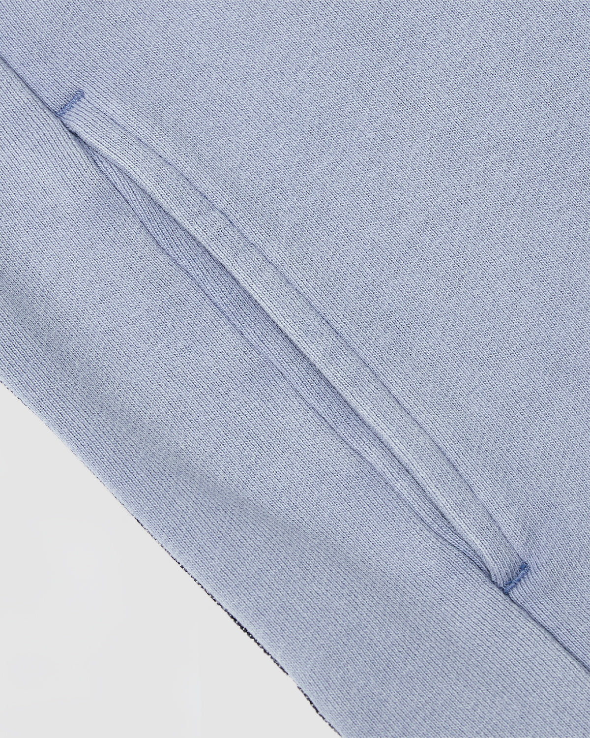 Close-up of Sundae School’s SKY BLUE TEARDROP KNOT SWEATSHIRT, highlighting the light blue 100% cotton knit fabric, diagonal slit pocket with denim trim, and detailed stitching and texture.