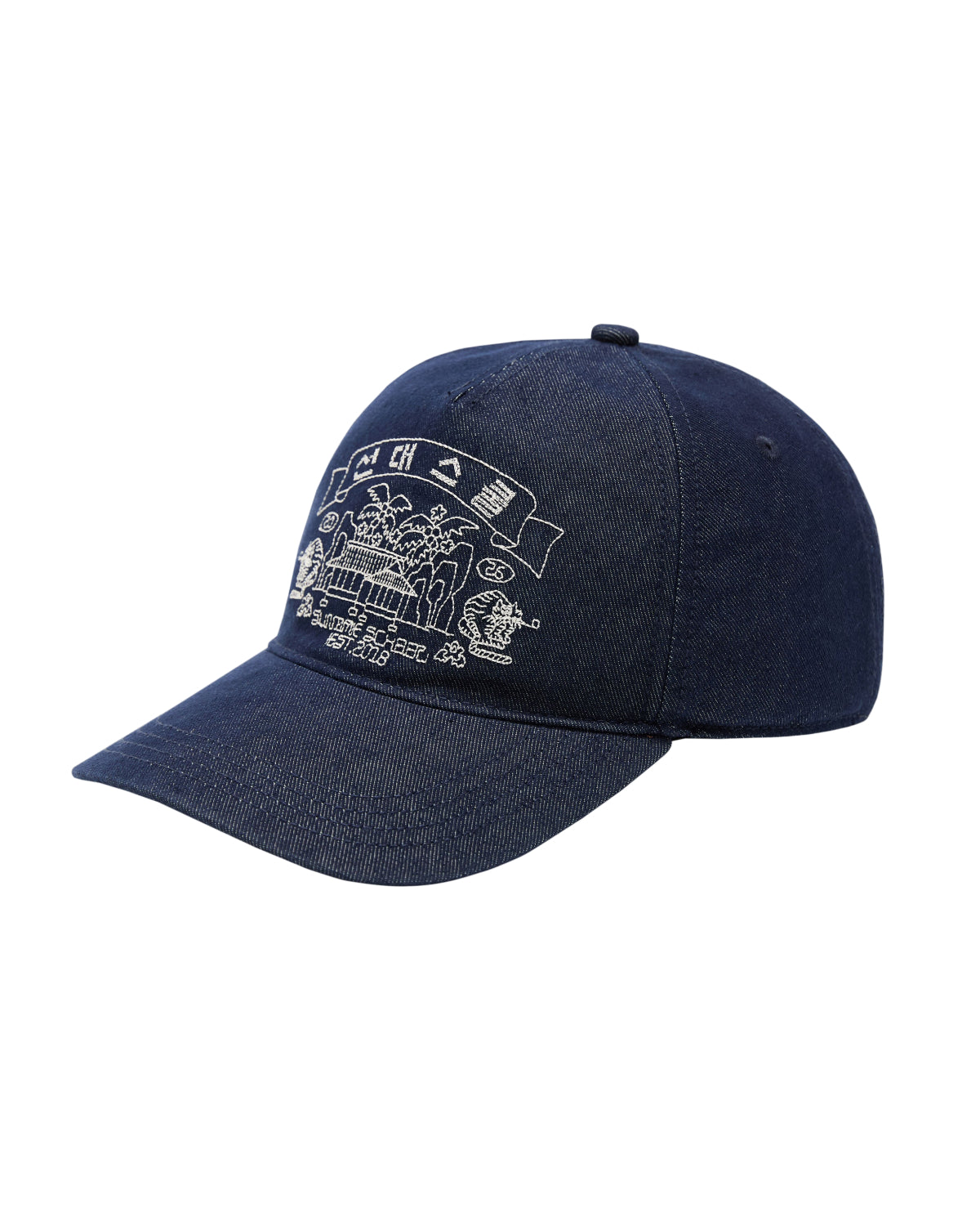The TIGER DEN CAP by Sundae School is a dark blue denim strapback hat made from a premium cotton blend, featuring white Korean folk-art embroidery of a building, trees, flags, and small decorative elements on the front.