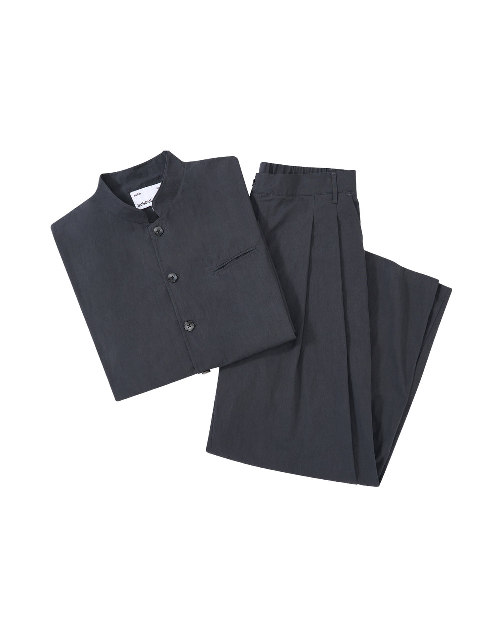 The CHARCOAL STAND COLLAR UNIFORM JACKET by Sundae School, made from a cotton nylon blend with buttons and a chest pocket, is neatly displayed with matching pleated trousers on a light gray background.