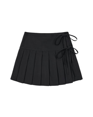 Introducing the BLACK UNIFORM APRON SKIRT by Sundae School—a black pleated mini skirt inspired by the sleek design of a Korean pleated apron. This modern piece features two ribbon tie accents on the right, a fitted waistband, and a flared, structured silhouette for a contemporary take on classic workwear style.