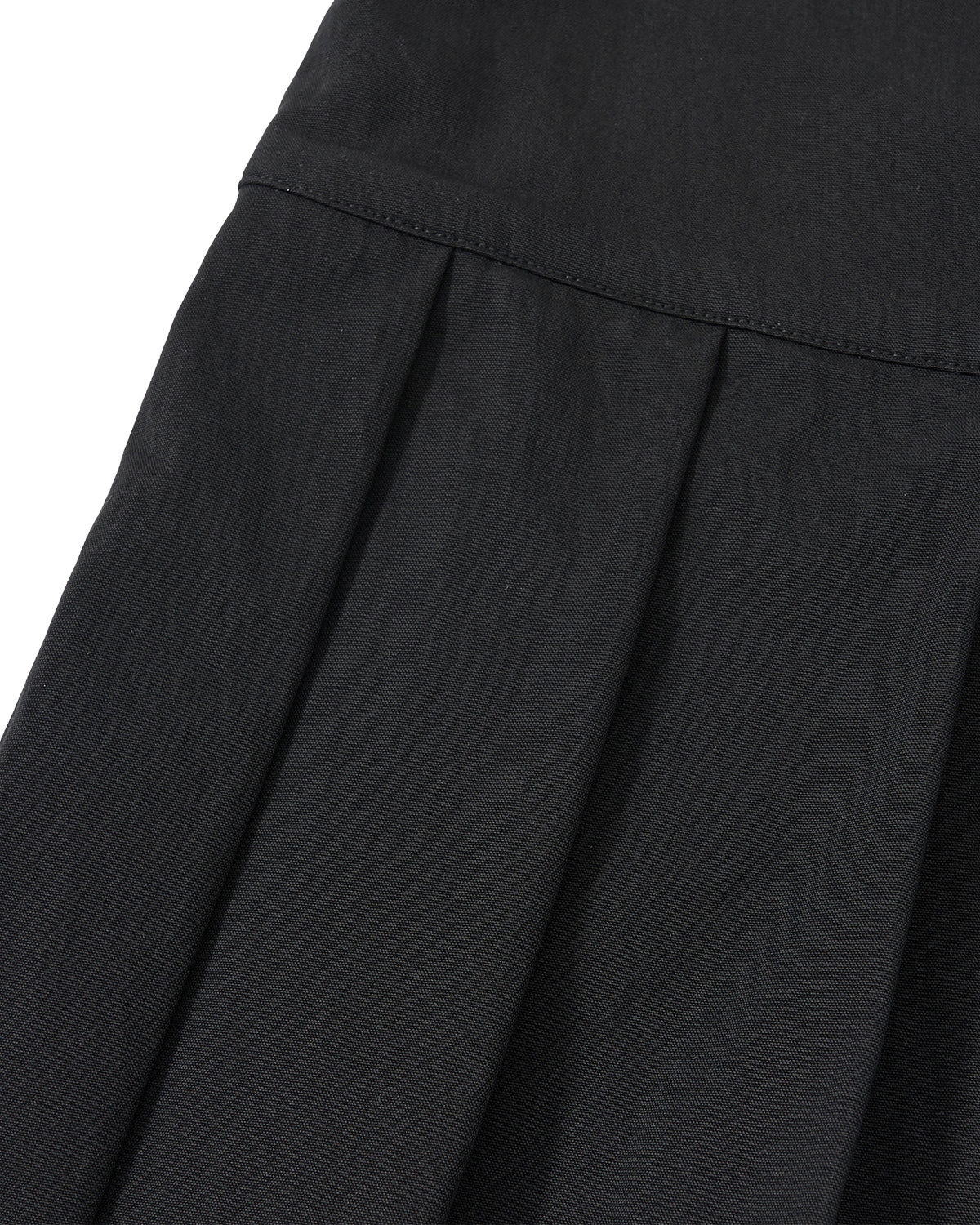 Close-up of the BLACK UNIFORM APRON SKIRT by Sundae School, featuring black pleated fabric with detailed stitching and folds.