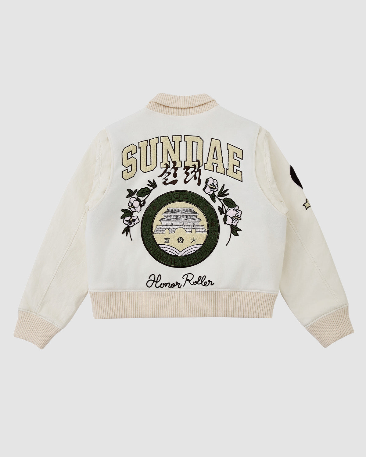 The IVORY VARSITY JACKET by Sundae School is a cream oversized varsity jacket with vegan leather sleeves, floral embroidery, SUNDAE and Korean text on the back, building patch, Aloner Roller text, and a star sleeve patch. Unisex streetwear.