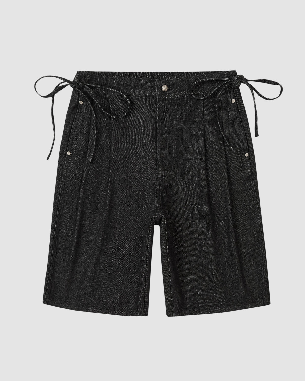 The BLACK VITA JORTS by Sundae School are black wide-leg denim shorts with an elastic waistband, side pleats, adjustable ties, and two metal snap buttons on each side at the waist. Shown against a plain light grey background.