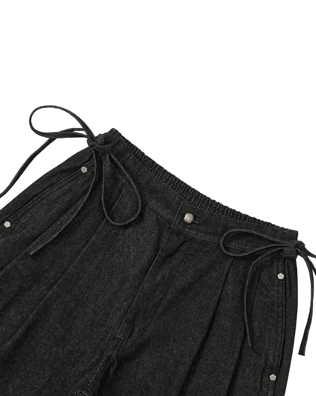 Close-up of Sundae School’s BLACK VITA JORTS, featuring an elastic waistband with silver snap buttons and hip ties, wide-leg silhouette, and laid flat against a white background.